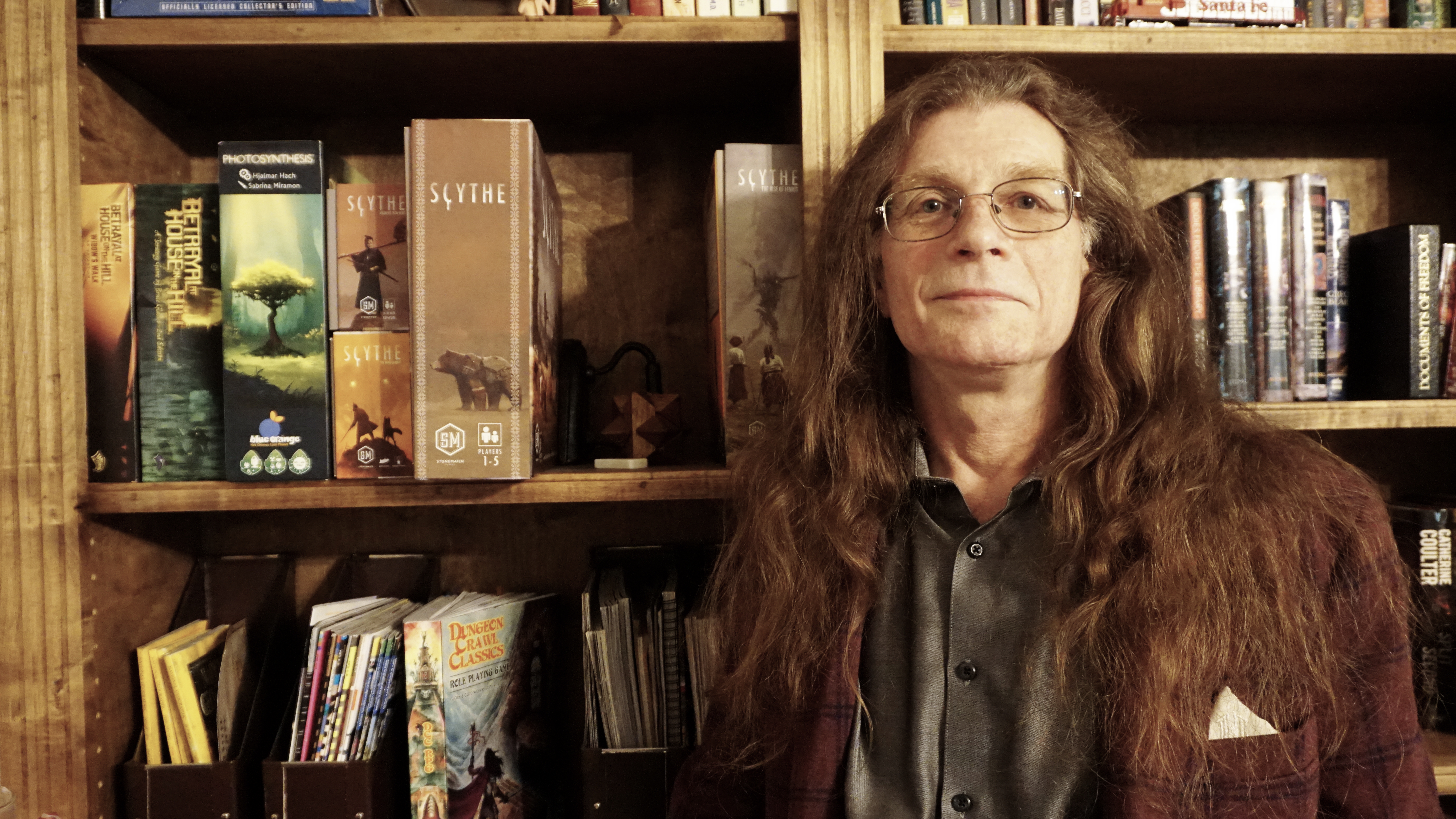 Dennis in front of his bookshelf in smoking jacket.